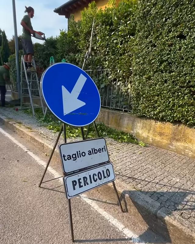 Potatura di una siepe lungo la strada con il cantiere segnalato
