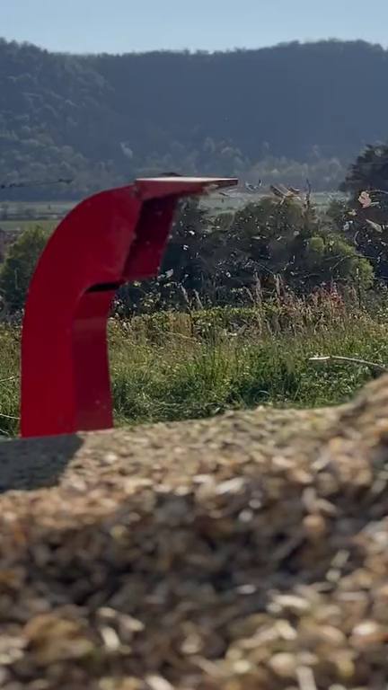 Cippatore al lavoro: il cippato esce dallo scivolo rosso