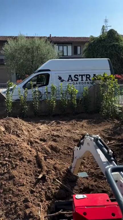 Miniescavatore al lavoro e furgone Astra Gardens sullo sfondo